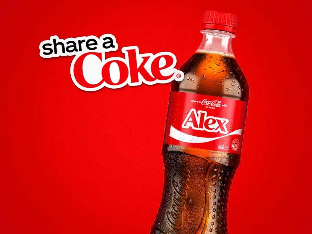 Najciekawsze reklamy zewnętrzne – przykłady i kreatywne kampanie, które musisz znać 6 Jest to grafika przedstawiająca kampanię marki Coca-Cola pod tytułem "Share a Coke", która jest jednym z przykładów personalizacji w reklamie.